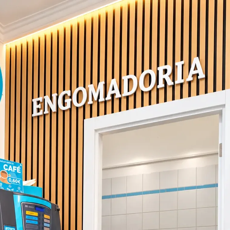 Cantinho da engomadoria, com o letreiro na parede e a máquina de café ao lado
