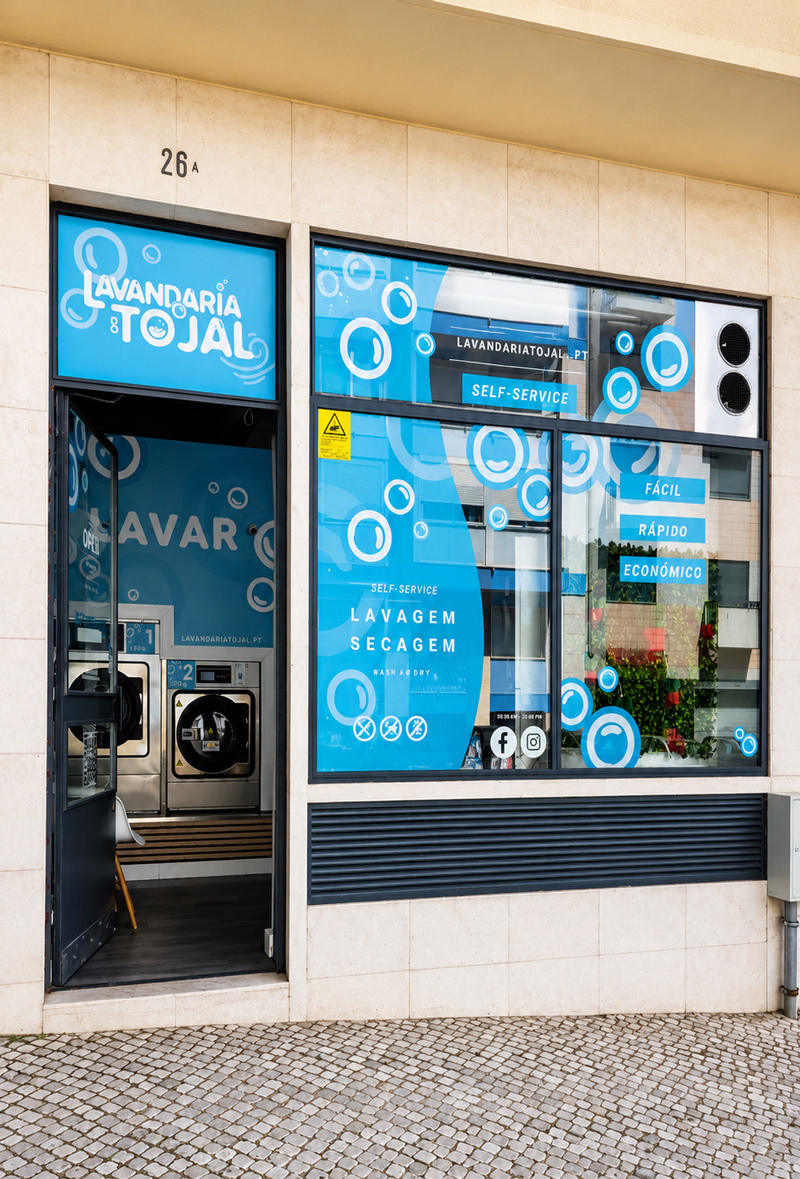 Fachada da Lavandaria do Tojal, com montras azuis e o logótipo sobre a porta